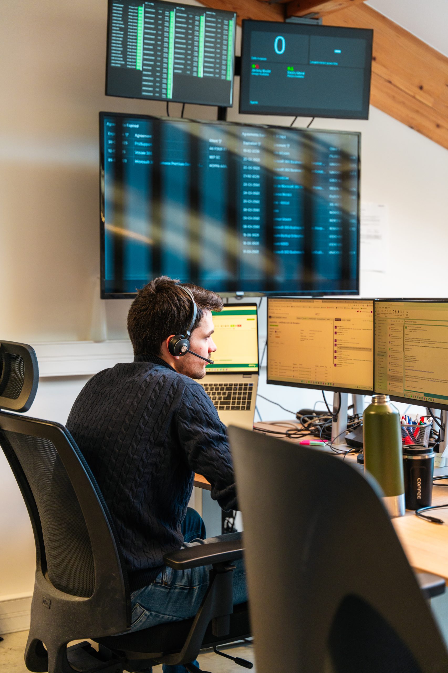 Agent helpdesk devant écrans de monitoring au travail
