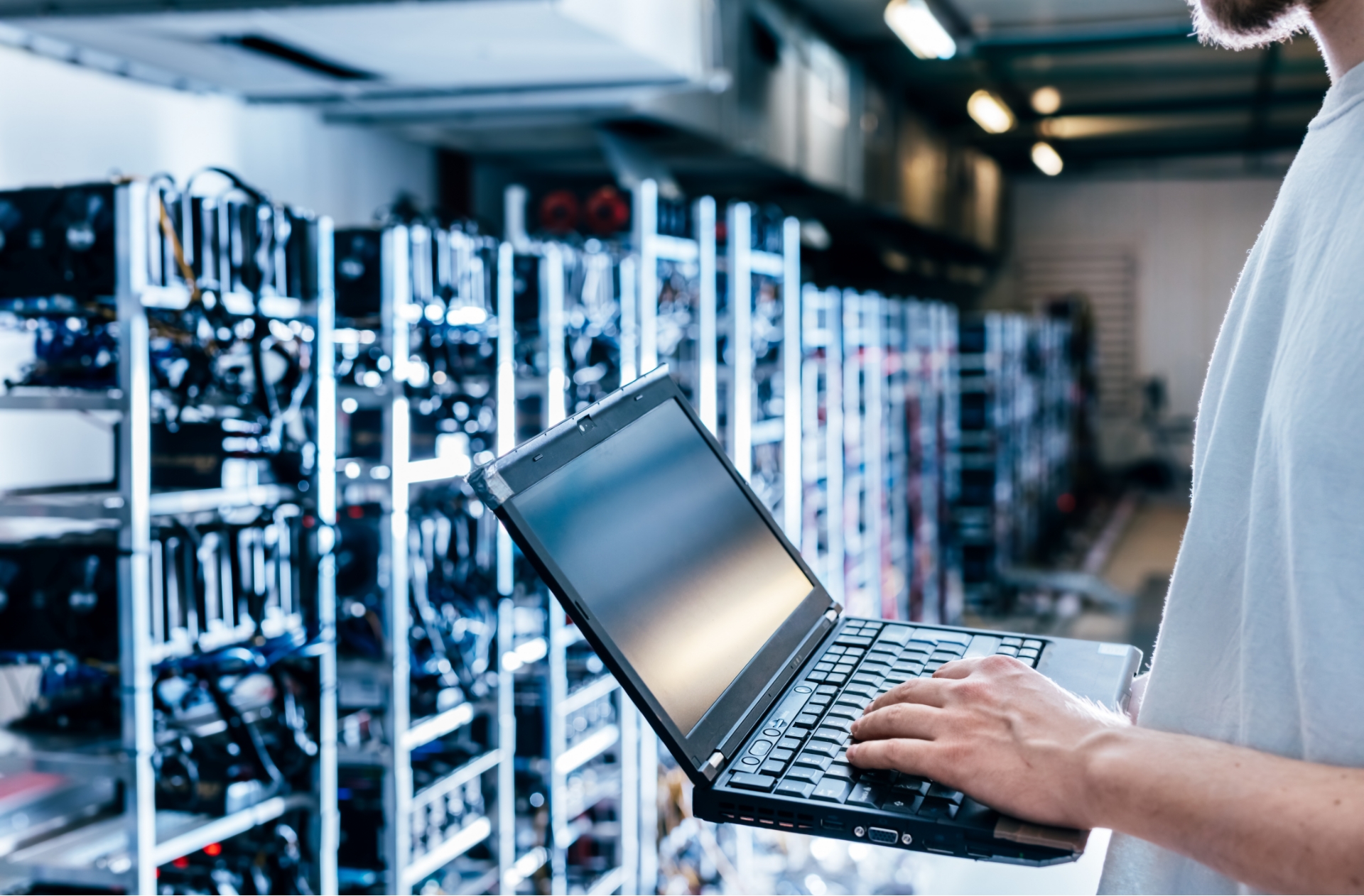 Technicien sur son pc devant racks de serveurs